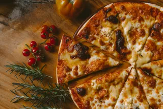 A sliced pizza with roasted cherry tomatoes and rosemary