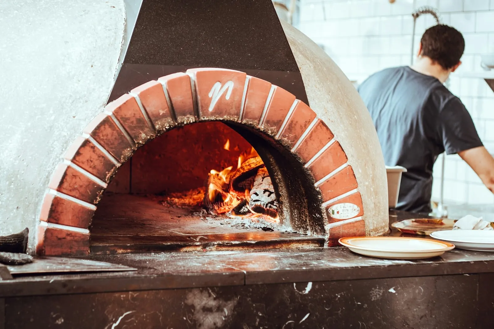 A pizzaiolo working beside a domed brick oven
