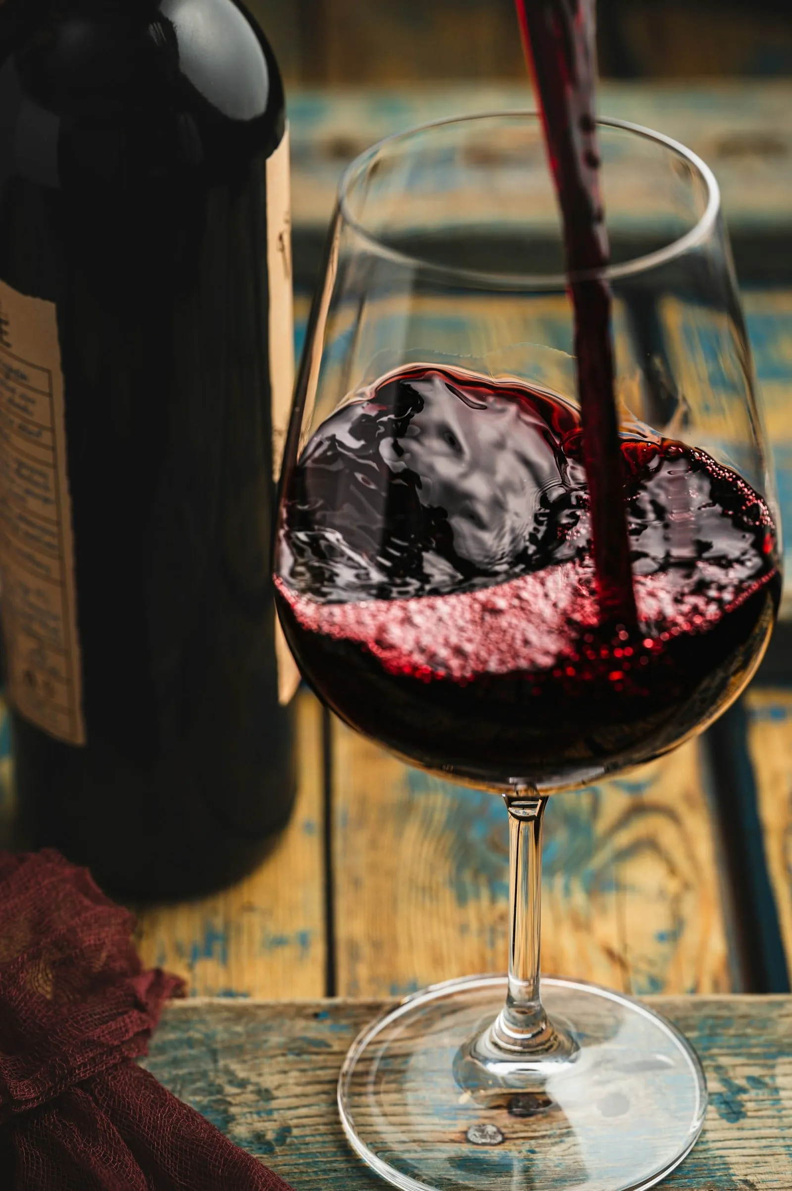 Red wine splashing into a glass beside the bottle