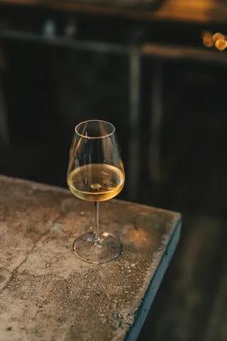 A glass of white wine on a stone ledge