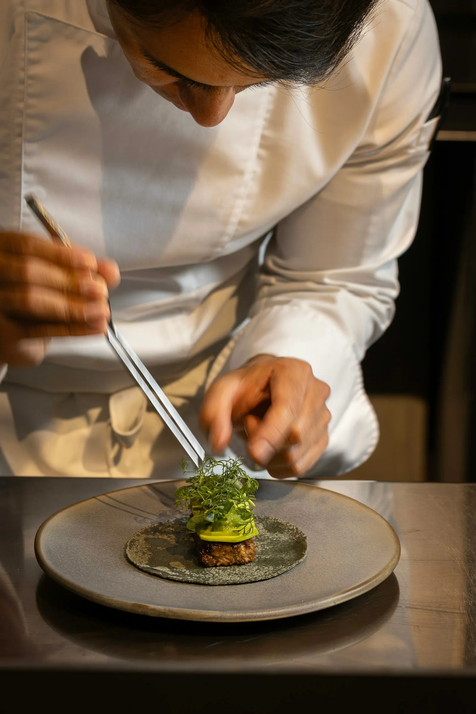 A chef finishing a dish at the pass