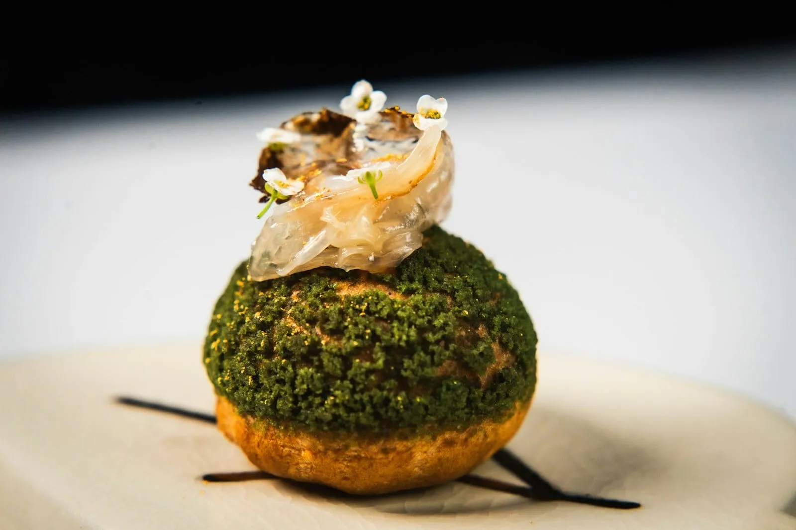 A green herb-crusted dome topped with a delicate garnish