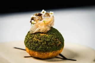 A green herb-crusted dome topped with a delicate garnish