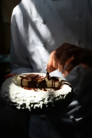 A chef presenting a plate of beef in dramatic light