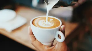A latte with milk being poured into it