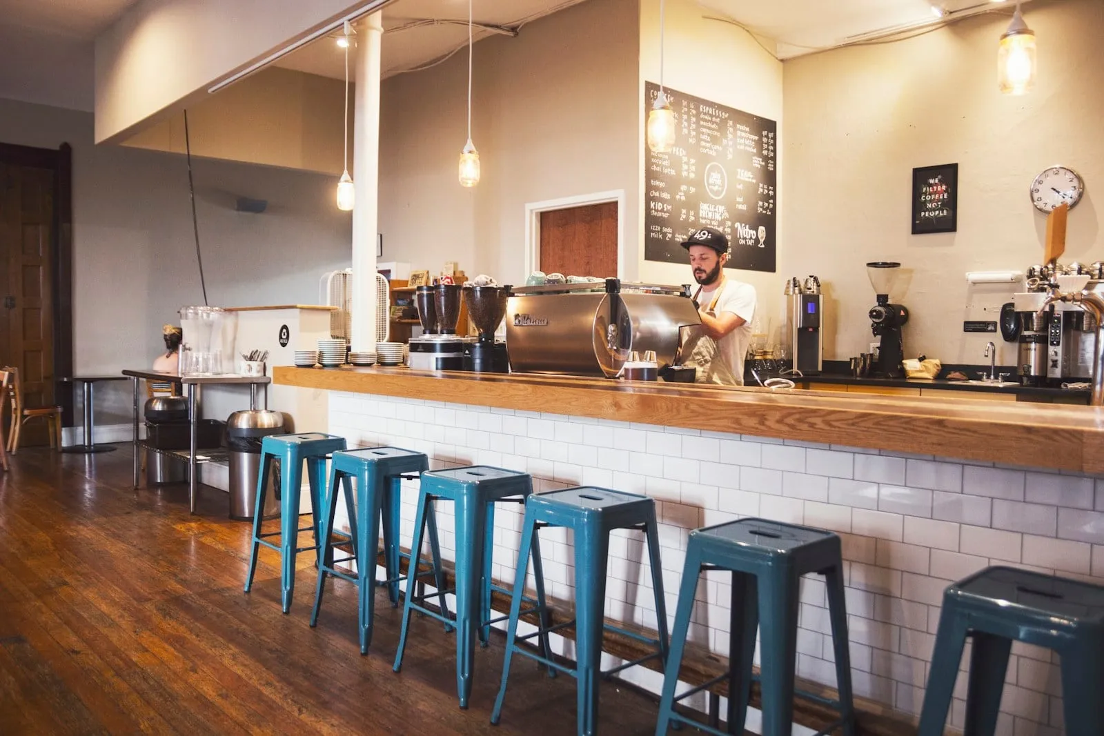 A coffee bar with blue metal stools and a white tile counter