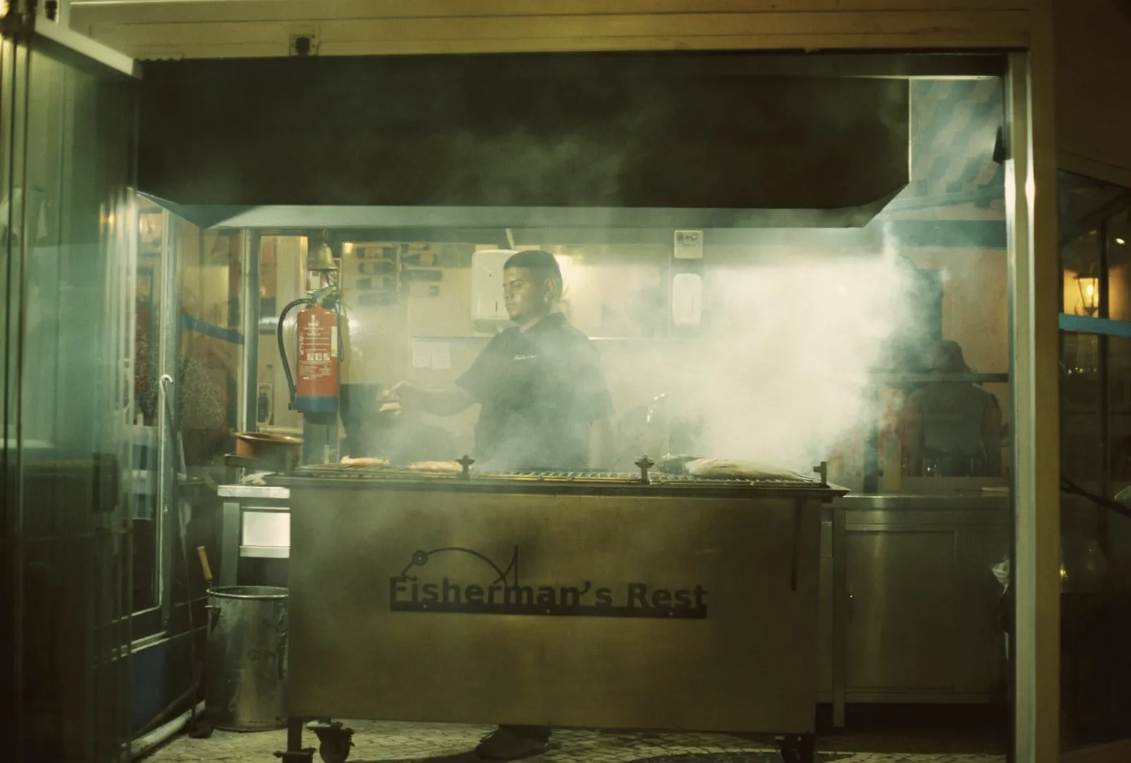 Smoke rising from the pit in a dim cook room