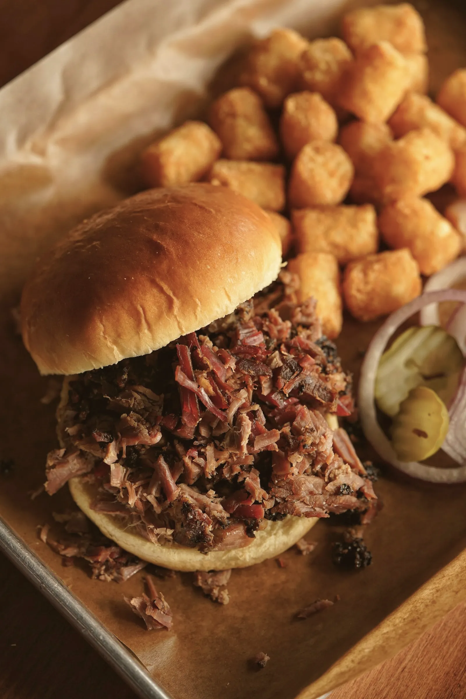 A pulled pork sandwich with a side of tater tots