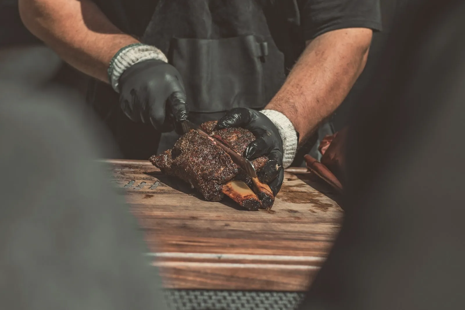 Gloved hands slicing brisket on a cutting board