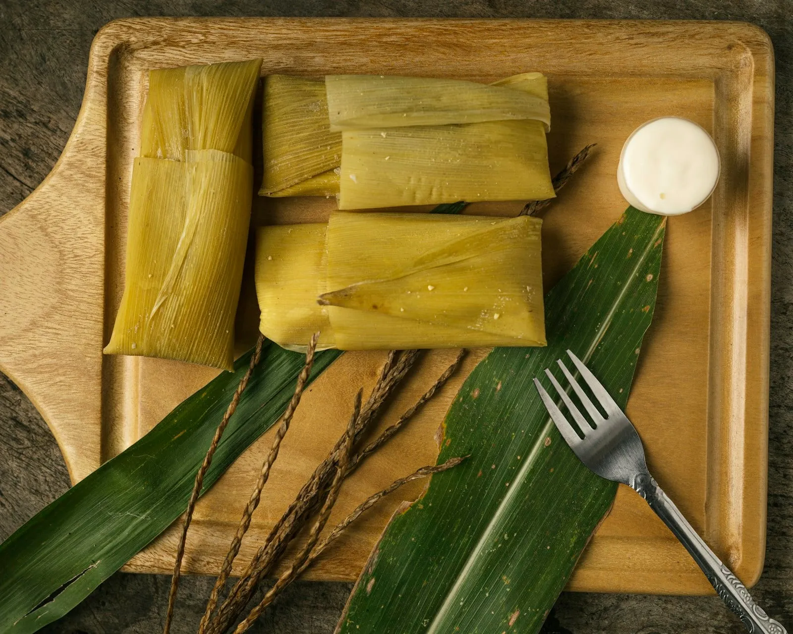 Tamales on a wooden board with corn husks