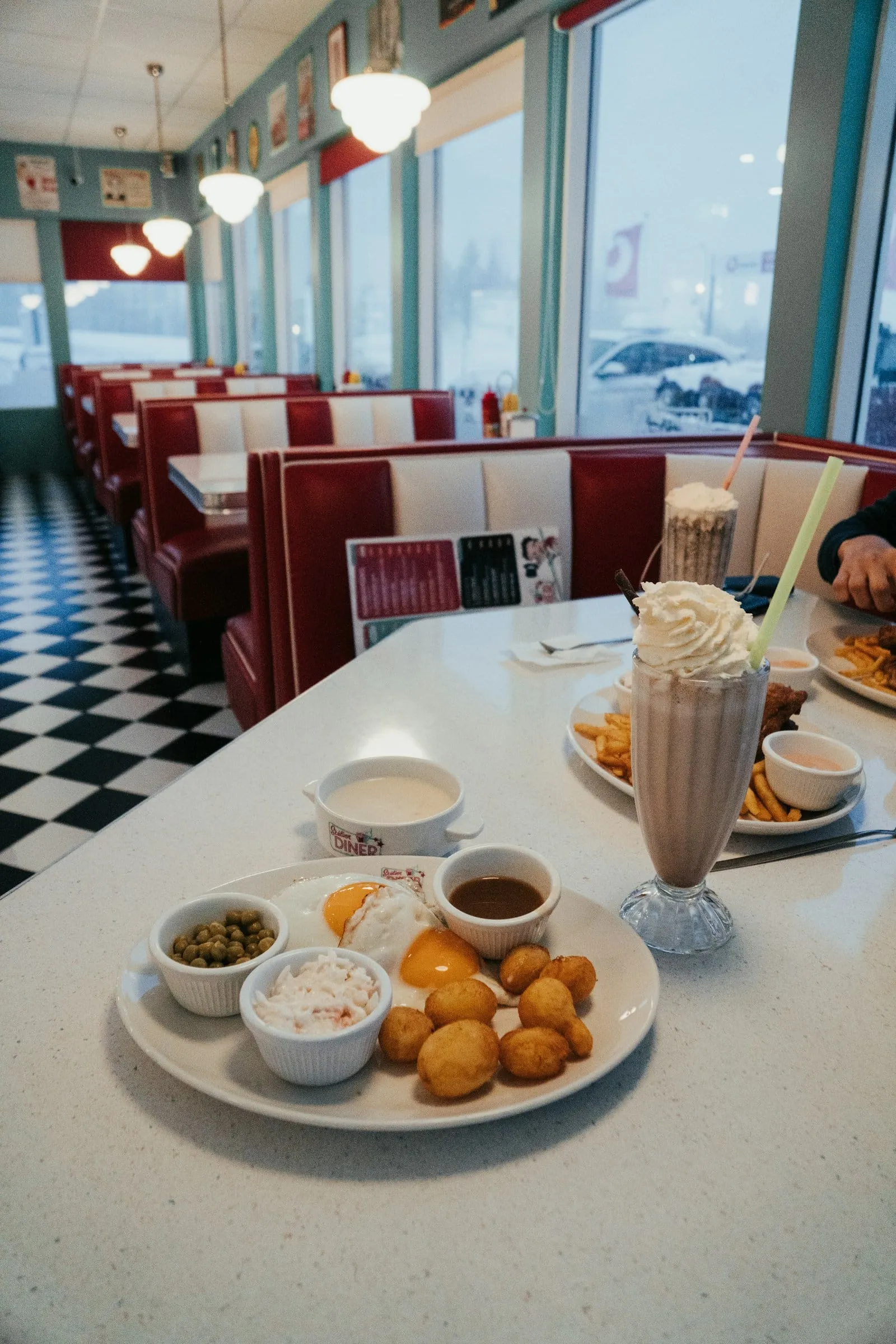 A booth by the window with a milkshake and fries on the table