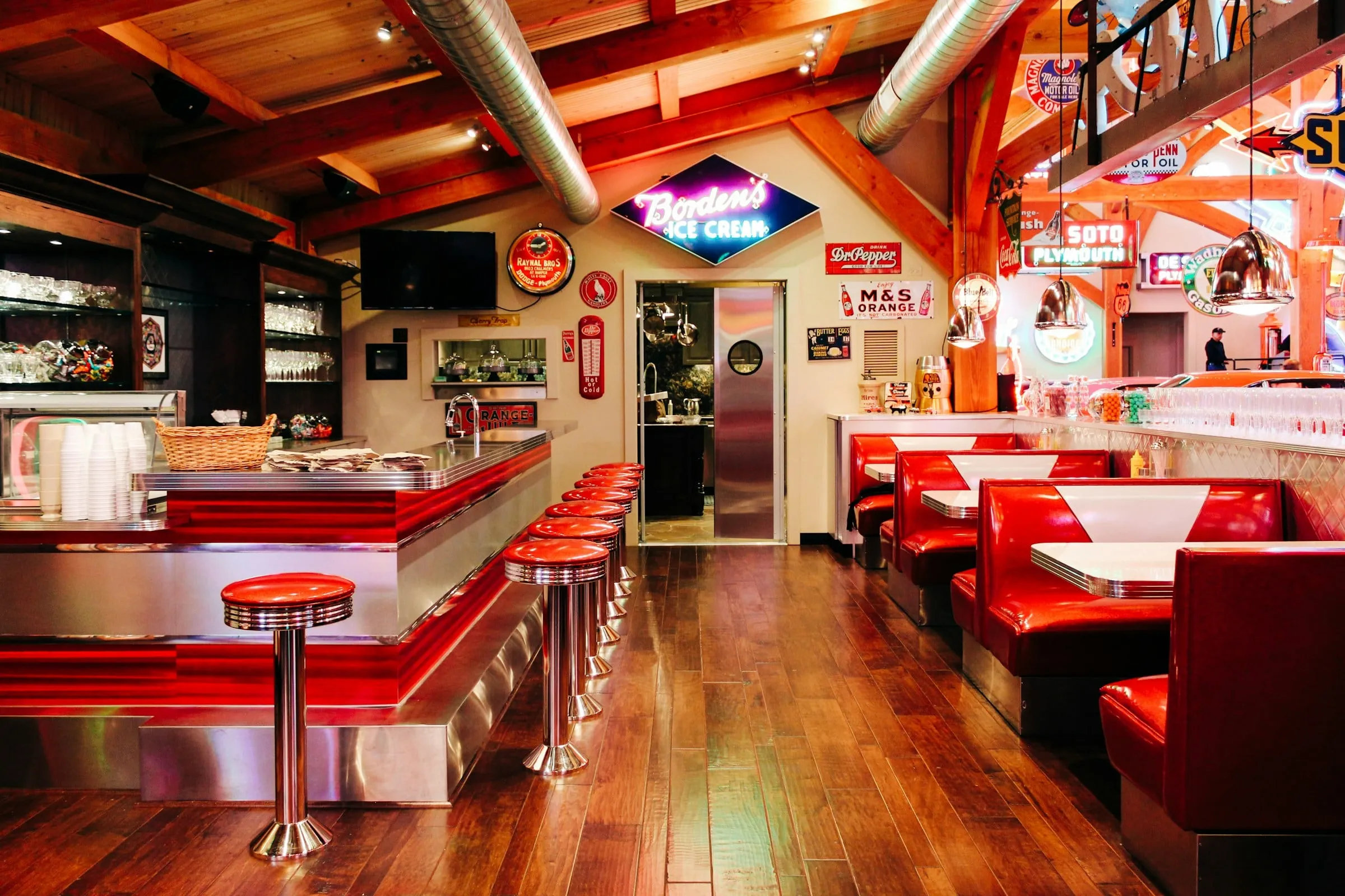 A long diner counter with red stools and a wood floor