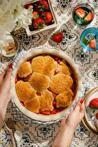 Peach cobbler with a golden biscuit crust in a round baking dish