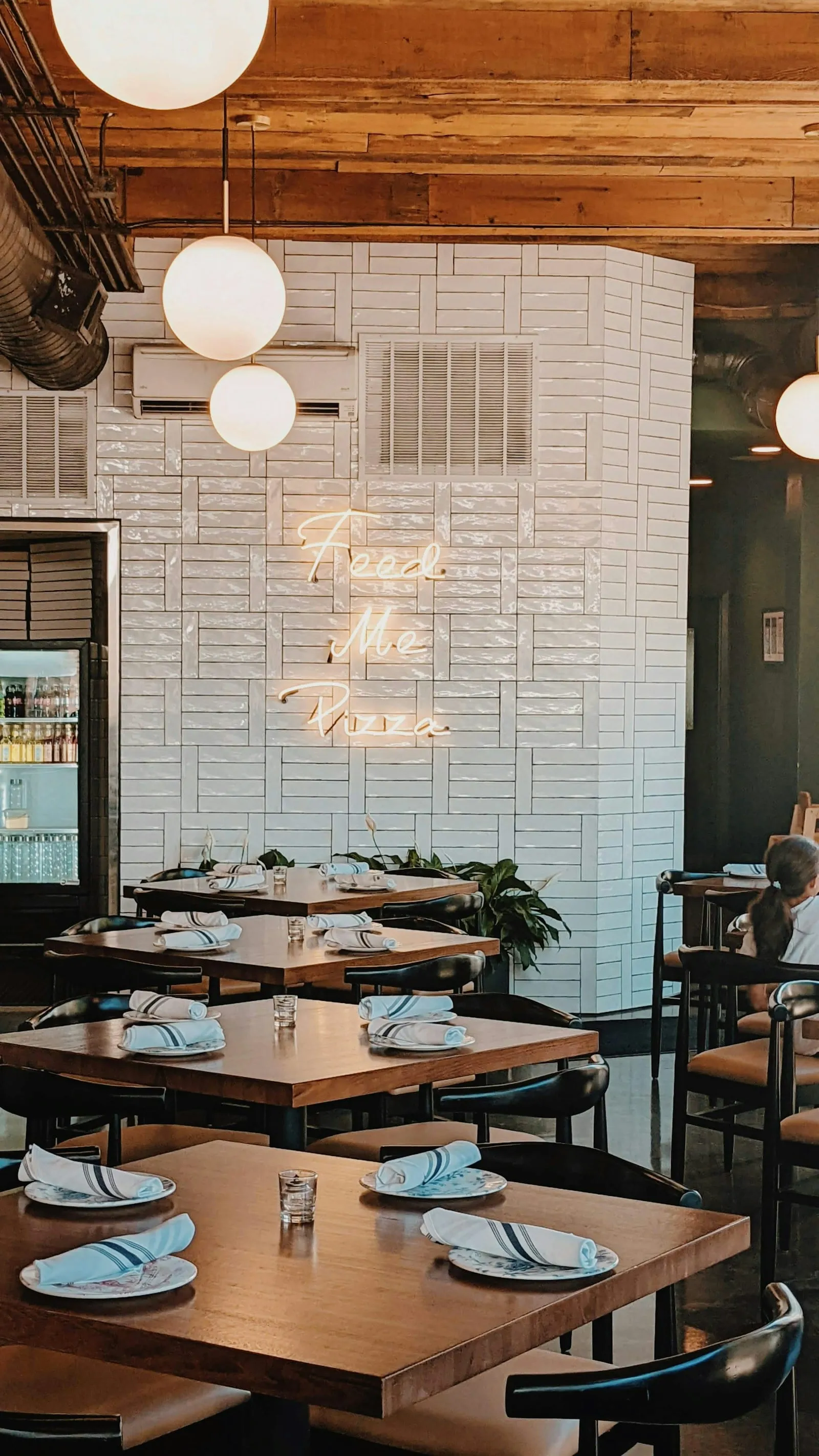 A corner of the dining room with white tile and wooden tables