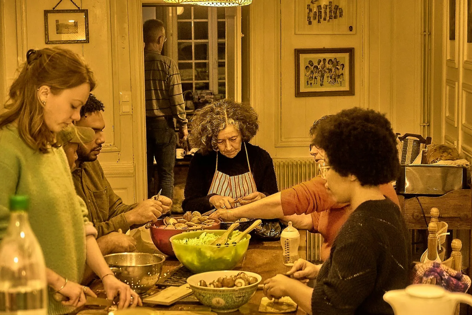 Three generations of a family cooking together around a kitchen table