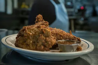 Fried chicken smothered in gravy on an oval diner plate