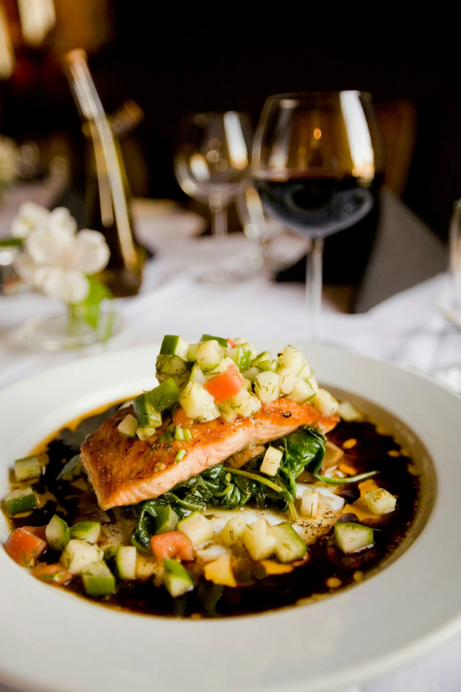 Grilled salmon over vegetables in a white bowl