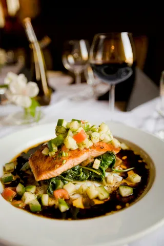 Grilled salmon over vegetables in a white bowl