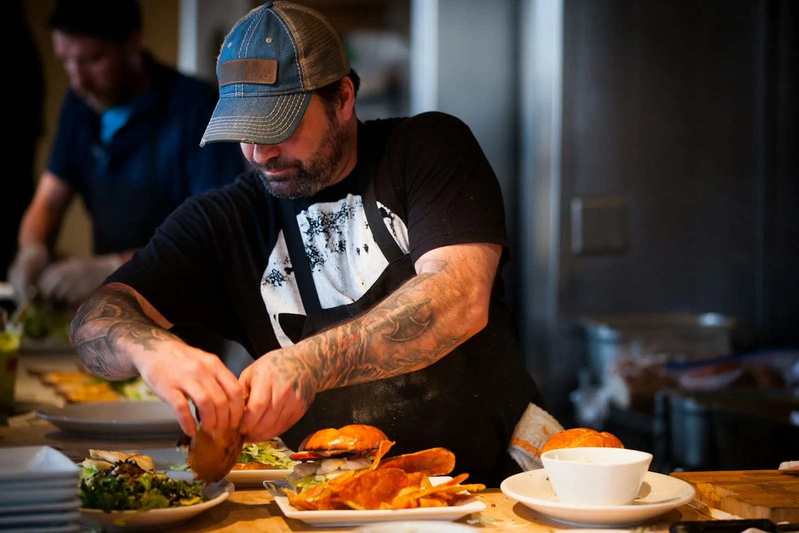 A cook in a cap plating burgers on the line