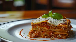 A slice of lasagna topped with basil