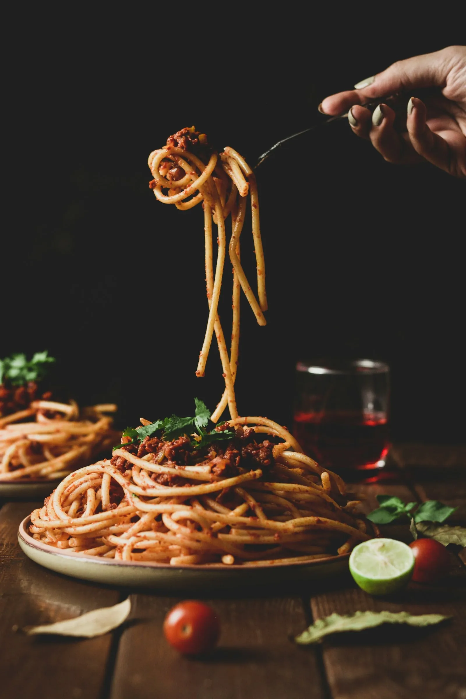 Spaghetti being twirled on a fork above the plate