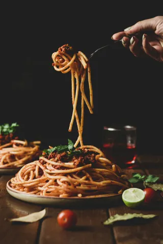 Spaghetti being twirled on a fork above the plate
