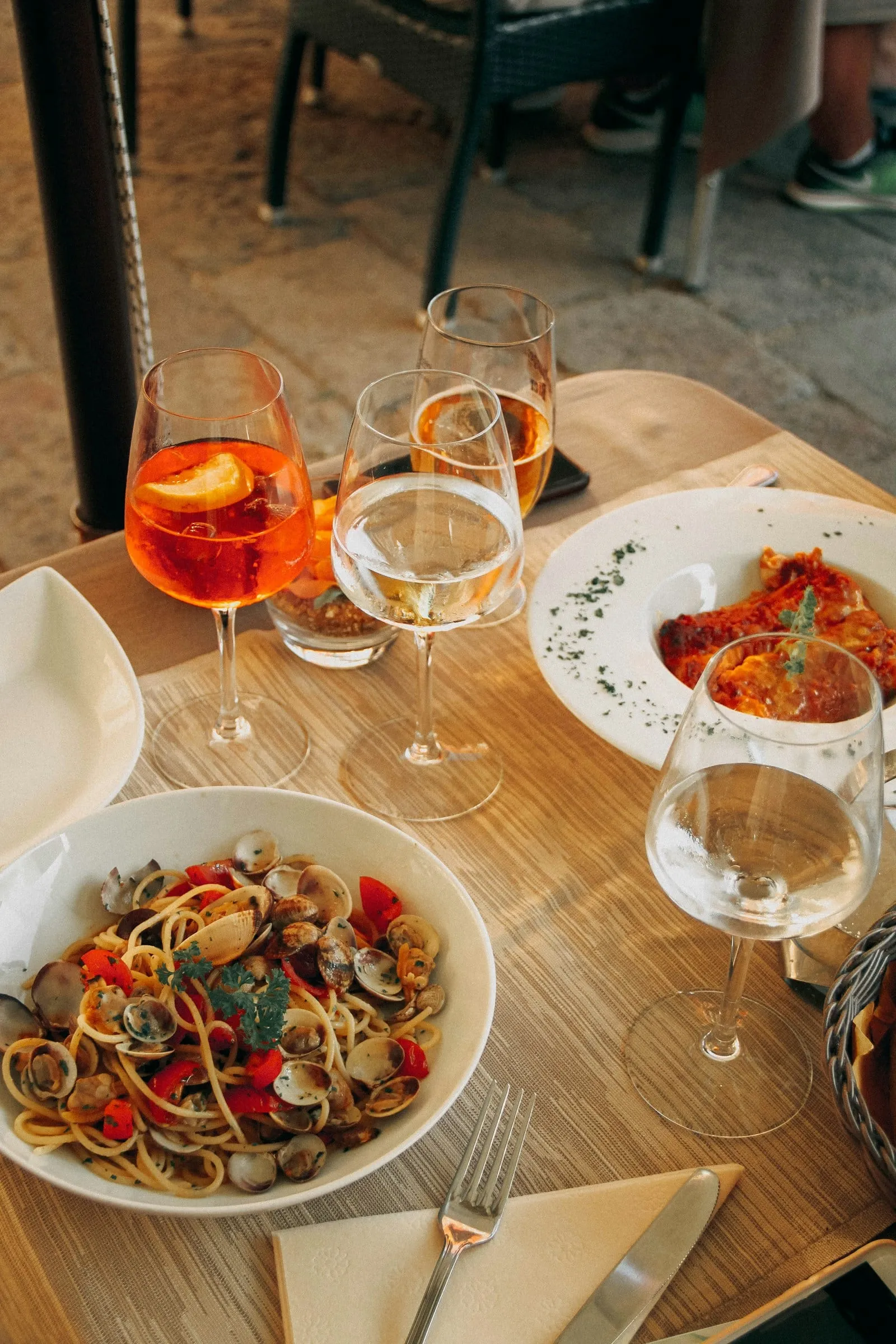 Plates of pasta and spritzes on a restaurant table