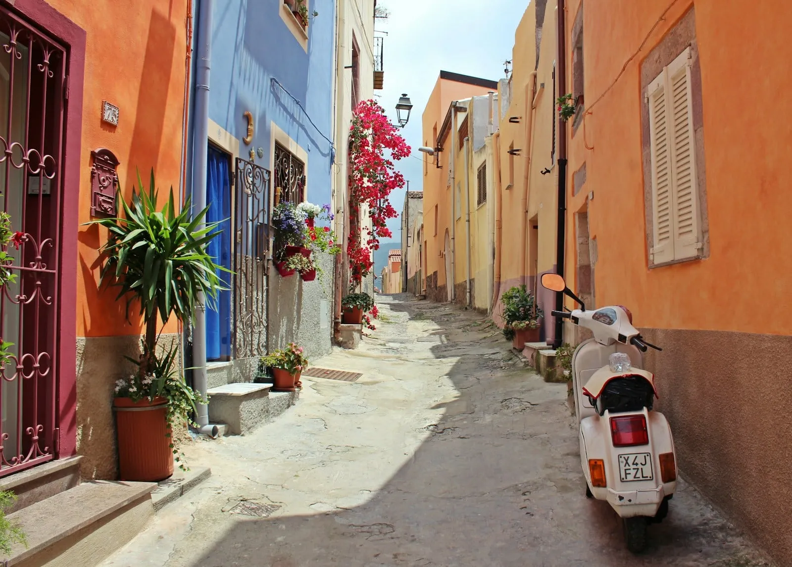 A narrow Italian street with colorful houses and a parked scooter